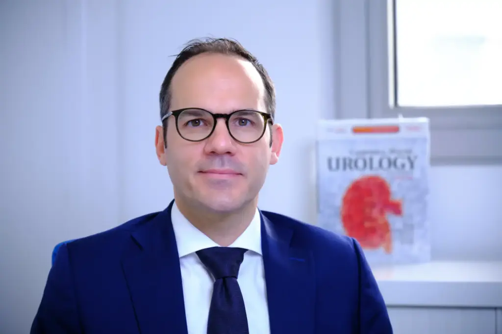 Prof. F.-X. Madec at his desk writing a scientific publication on urethral stricture disease, with urology reference books, highlighting expertise in complex and recurrent cases